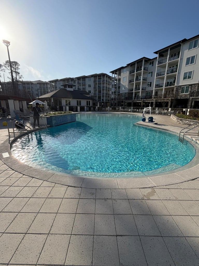 Outdoor swimming pool with turquoise water surrounded by apartment buildings on a sunny day