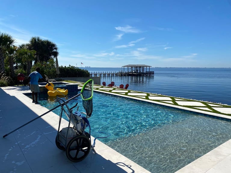 Colorful bicycle parked by a tropical poolside with clear blue water, palm trees, and a pier extending into calm ocean waters